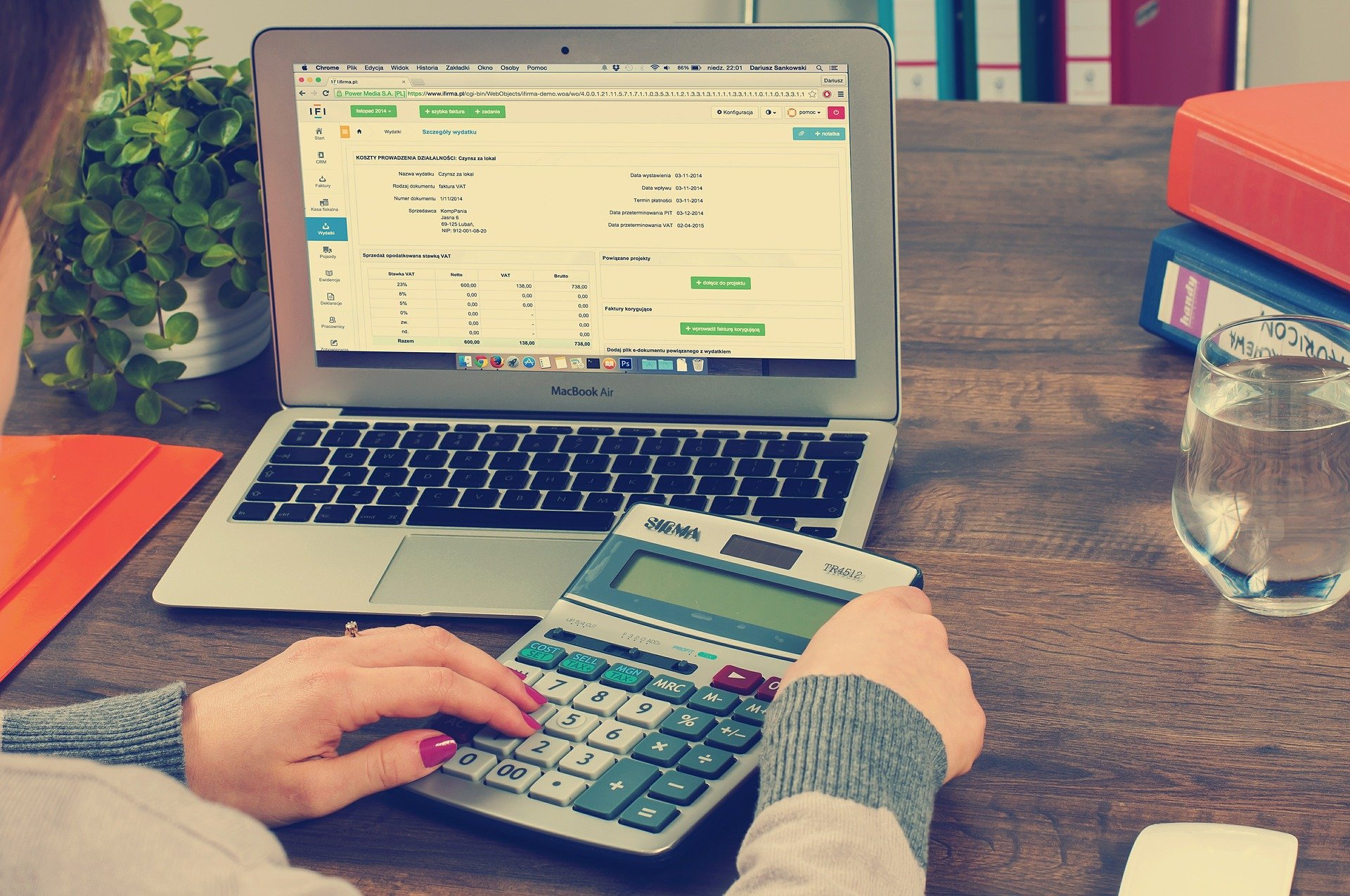 An image of a woman using her laptop and a calculator to go over finances