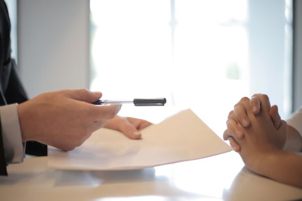 agent handing contract and pen to individual