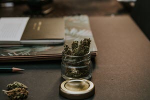 glass jar full of cannabis sitting on a desk
