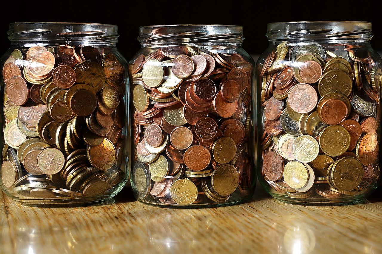 An image of three mson jars filled up with coins that someone was saving for a large purchase