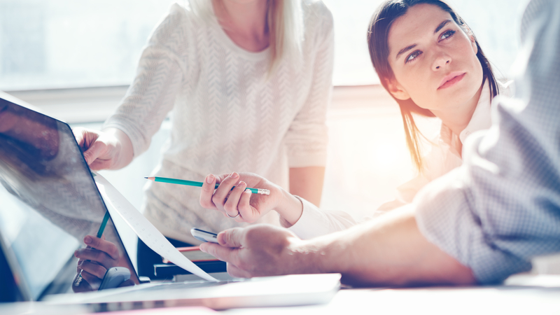 woman pointing at computer with colleague