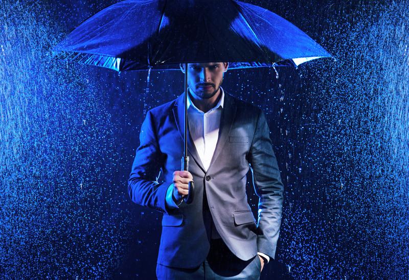 a man standing on a stage with a blue umbrella